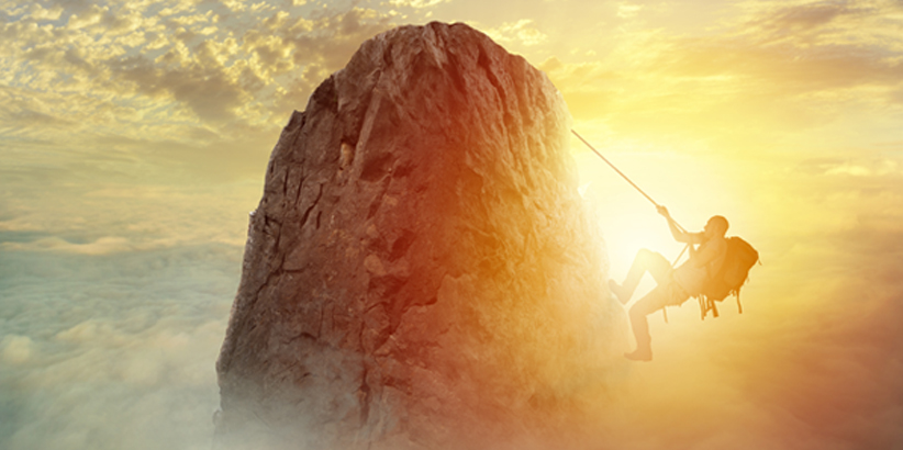 Person climbing a mountain with a sun rising in the background