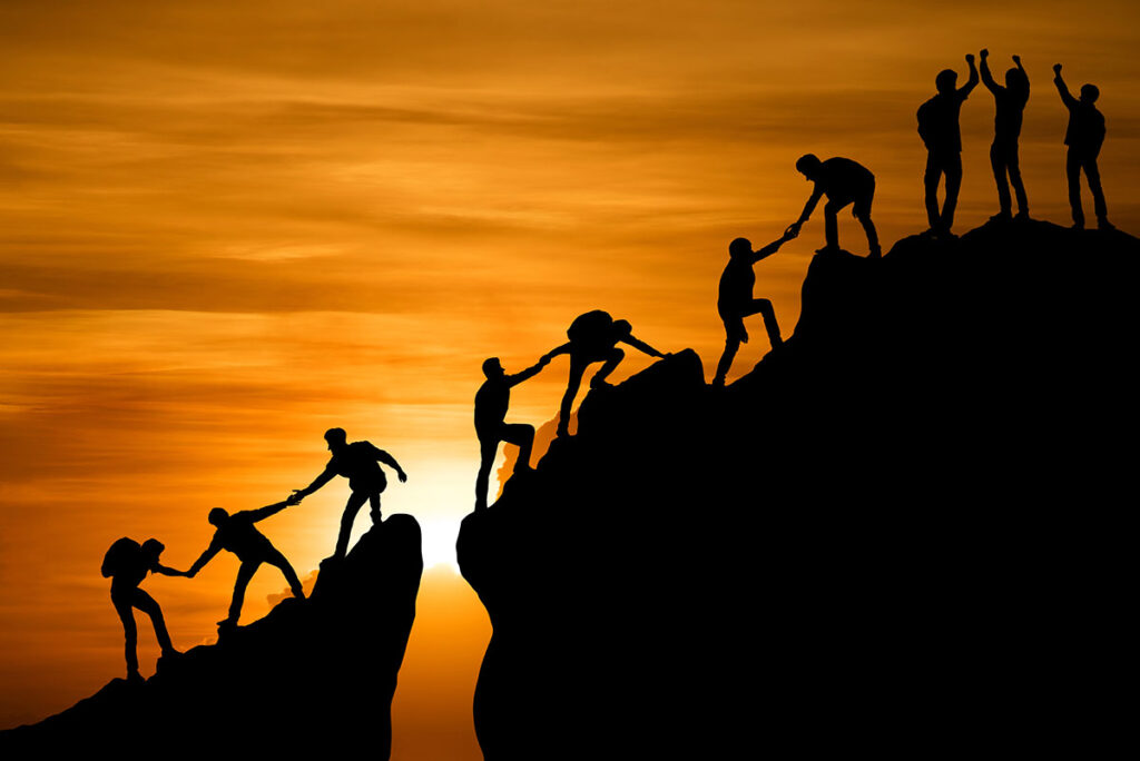 People helping others up a mountain