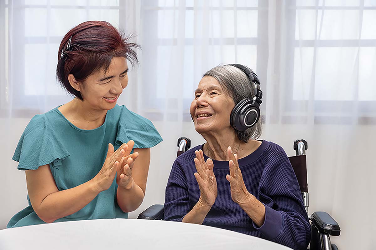 Two women clapping, one has headphones on