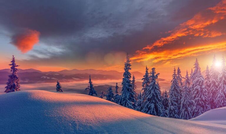 Snow covered hills with trees and sunset