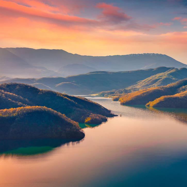 Still water nestled in mountains w sunset